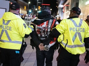 Police take a person into custody as they worked to clear an area on Rideau Street, during a convoy-style protest participants are calling "Rolling Thunder," in Ottawa, on Friday, April 29, 2022. The public inquiry into the federal government's unprecedented use of the Emergencies Act during what organizers called "Freedom Convoy" protests last winter begins on Thursday and 65 witnesses, including Prime Minister Justin Trudeau and high profile convoy organizers, are expected to testify.