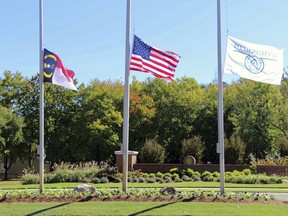 The North Carolina flag, American flag and Hedingham flag all fly at half-staff at the entrance to the Hedingham Golf Club in Raleigh, N.C., on Friday, Oct. 14, 2022, after a shooting in the community left five dead Thursday night, including one off-duty police officer.