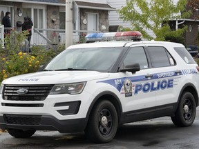 A police vehicle is shown outside a house in Laval, Que., Tuesday, October 18, 2022. Police near Montreal say two children are dead and a 46-year-old man is under arrest after officers made a grim discovery Monday.