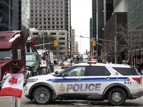 An Ottawa Police vehicle blocks off Kent Street in front of parked trucks during the "Freedom Convoy" protest in Ottawa on Sunday, Feb. 6, 2022. The city of Ottawa opened its books to show how much the "Freedom Convoy" protest last winter cost, and the pressure it placed upon city services.
