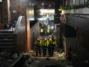 Police officers inspect the scene where people died and were injured in Seoul, South Korea, Sunday, Oct. 30, 2022, after a mass of mostly young people celebrating Halloween festivities in Seoul became trapped and crushed as the crowd surged into a narrow alley.