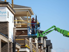 A construction worker works from a lift in a new housing development in Ottawa on Friday, Oct. 14, 2022.&ampnbsp;Ontario is planning to double the maximum fines for new homebuilders and sellers who unfairly cancel a project or purchase agreement. THE&ampnbsp;CANADIAN PRESS/Sean Kilpatrick