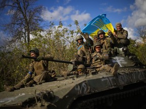 Ukrainian soldiers sit on an armoured vehicle as they drive on a road between Izium and Lyman in Ukraine, Tuesday Oct. 4, 2022.