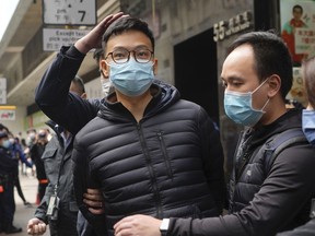 FILE - Editor of Stand News Patrick Lam, center, is escorted by police officers into a van after they searched evidence at his office in Hong Kong on Dec. 29, 2021. A sedition trial opened in Hong Kong on Monday, Oct. 31, 2022, for the online media outlet's acting editor-in-chief Lam and editor-in-chief Chung Pui-kuen.
