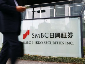 FILE - A person walks past a signboard of SMBC Nikko Securities in Tokyo on March 24, 2022. Japan's Financial Services Agency on Friday, Oct. 7, 2022 ordered brokerage SMBC Nikko Securities to suspend its block trading operations for three months as part of penalties in a market manipulation case. (Kyodo News via AP, File)