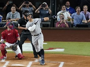 New York Yankees' Aaron Judge follows through on a solo home run, his 62nd of the season, as Texas Rangers catcher Sam Huff, left, and umpire Randy Rosenberg, rear, look on in the first inning of the second baseball game of a doubleheader in Arlington, Texas, Tuesday, Oct. 4, 2022. With the home run, Judge set the AL record for home runs in a season, passing Roger Maris.
