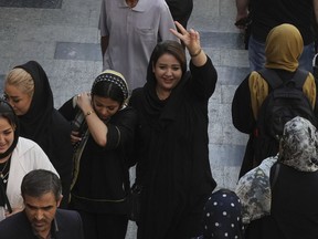 A woman flashes a victory sign as she walks around in the old main bazaar of Tehran, Iran, Saturday, Oct. 1, 2022. Thousands of Iranians have taken to the streets over the last two weeks to protest the death of Mahsa Amini, a 22-year-old woman who had been detained by the morality police in the capital of Tehran for allegedly wearing her mandatory Islamic veil too loosely.
