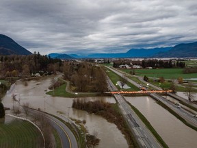 A dam is placed across all lanes of the closed Trans-Canada Highway near the flooded Sumas River, in Abbotsford, B.C., on Wednesday, Dec. 1, 2021.