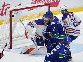 Vancouver Canucks' Nils Hoglander (21), of Sweden, scores against Edmonton Oilers goalie Stuart Skinner (74) during the first period of a pre-season NHL hockey game in Abbotsford, B.C., on Wednesday, October 5, 2022.