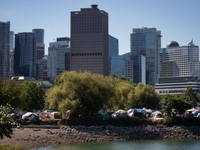 Tents are seen at a homeless encampment at Crab Park as the downtown skyline rises behind them in Vancouver, on Sunday, August 14, 2022. Police say one suspect is in custody after a "stabbing spree" in downtown Vancouver's Crab Park.