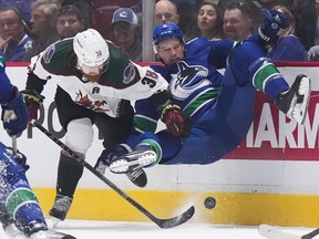 Vancouver Canucks' Tucker Poolman, right, is upended by Arizona Coyotes' Liam O'Brien (38) during the first period of a pre-season NHL hockey game in Vancouver, on Friday, Oct. 7, 2022.