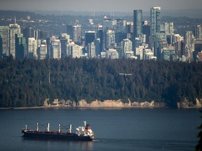 A bulk carrier cargo ship travels into port as a Harbour Air seaplane flies towards Stanley Park and the downtown skyline, in Vancouver, on Wednesday, July 27, 2022. The government of British Columbia will not support an Indigenous-led bid to host the 2030 Olympics in the province.