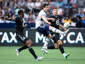 Vancouver Whitecaps' Brian White, centre, receives a pass between Minnesota United's Bakaye Dibassy, left, and Michael Boxall during the second half of an MLS soccer game in Vancouver, B.C., Friday, July 8, 2022.