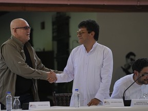 Antonio Garcia, of the Colombian guerrilla National Liberation Army (ELN), left, shakes hands with Ivan Danilo Rueda, High Commissioner for Peace on behalf of the Colombian government, after signing an agreement to resume peace talks, at the Casa Cultural Aquiles Nazoa in Caracas, Venezuela, Tuesday, Oct. 4, 2022. The agreement comes after more than four years of suspension, and will start in November.