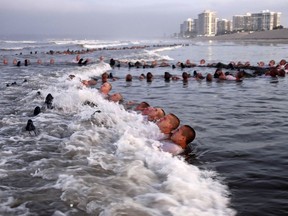 FILE - U.S. Navy SEAL candidates, participate in "surf immersion" during Basic Underwater Demolition/SEAL (BUD/S) training at the Naval Special Warfare (NSW) Center in Coronado, Calif., on May 4, 2020. Navy officials and a new report say the Naval Special Warfare Command has reprimanded three officers in connection with the February 2022 death of SEAL candidate Kyle Mullen, who collapsed and died of acute pneumonia just hours after completing the grueling Hell Week test.