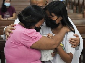 Catholic priest Flaviano "Flavie" Villanueva comforts relatives as they receive the urn containing the remains of victims of alleged extrajudicial killings at a church in Quezon city, Philippines, Wednesday, Sept. 28, 2022. A program was created to assist in getting a final resting place for exhumed remains of alleged victims of former Philippine President Rodrigo Duterte's "war on drugs."