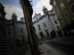 A Catholic church is reflected on a shop window in downtown Lisbon, Tuesday, Oct. 11, 2022. The head of a lay committee looking into historic child sex abuse in the Portuguese Catholic Church said Tuesday in a news conference that the problem has in the past been "widespread" and on some occasions reached "truly endemic" proportions.