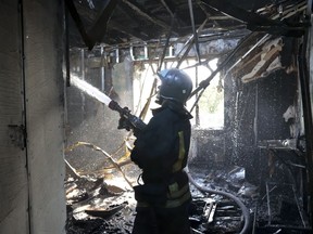 A firefighter works at the site of the burning after shelling in Donetsk, the capital of Donetsk People's Republic, eastern Ukraine, Sunday, Oct. 16, 2022.
