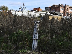 The tail of a missile sticks out in a residential area in the retaken village of Bohorodychne, eastern Ukraine, Saturday, Oct. 22, 2022.