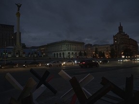 Cars pass in Independence Square at twilight in Kyiv, Ukraine, Monday, Oct. 31, 2022. Rolling blackouts are increasing across Ukraine as the government rushes to stabilise the energy grid and repair the system ahead of winter.