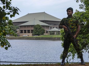 FILE- An army soldier soldier stands guard outside the parliament building in Colombo, Sri Lanka, Saturday, July 16, 2022. Sri Lankan lawmakers began debating a proposed constitutional amendment on Thursday that would trim the powers of the president, a key demand of protesters who are seeking political reforms and solutions to the country's dire economic crisis. The bill will be debated on Thursday, Oct. 20, and Friday and a vote will be held on Friday. It must be approved by two-thirds of the 225-member Parliament to become law.