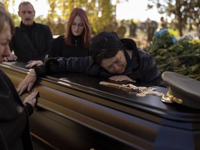 Tatiana Alexeyevna mourns over the coffin of her soon Colonel Oleksiy Telizhenko during his funeral in Bucha, near in Kyiv, Ukraine, Tuesday, Oct. 18, 2022. In March, Colonel Oleksiy was abducted by Russian soldiers from his home in Bucha, six months later his body was found with signals of torture buried in a forest not far away from his village.