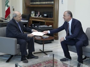 In this photo released by Lebanon's official government photographer Dalati Nohra, Lebanese President Michel Aoun, left, receives the final draft of the maritime border agreement between Lebanon and Israel from the deputy of Lebanese prime minister Elias Bou Saab and who leads the Lebanese negotiations, in Beirut, Lebanon, Tuesday, Oct. 11, 2022. Israel's prime minister said Tuesday that the country has reached an "historic agreement" with neighboring Lebanon over their shared maritime border after months of U.S.-brokered negotiations.