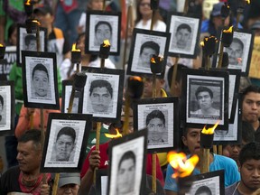 FILE - Family members of 43 missing teachers college students carry pictures of the students as they march with supporters to demand the case not be closed and that experts' recommendations about new leads be followed, in Mexico City, Tuesday, April 26, 2016. A group of international experts investigating the 2014 disappearance of 43 students in southern Mexico warned Monday, Oct. 31, 2022, that an attempt by the government to accelerate the results has created a "crisis" for the investigation and risks diminishing confidence in the outcome.