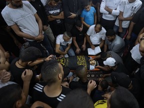 Mourners gather around the body of Palestinian Mahmoud Al-Sous, covered Islamic Jihad militant group flag, during his funeral in the West Bank town of Jenin, Saturday, Oct. 8, 2022. Israeli soldiers shot and killed two Palestinians on Saturday in an exchange of fire that erupted during a military raid in the West Bank. The Israeli military said it had arrested a 25-year-old operative from the Islamic Jihad militant group who has previously been imprisoned by Israel. It said the man had recently been involved in shooting attacks on Israeli soldiers.