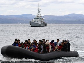 FILE - Migrants arrive with a dinghy accompanied by a Frontex vessel at the village of Skala Sikaminias, on the Greek island of Lesbos, after crossing the Aegean sea from Turkey, on Feb. 28, 2020. A much-anticipated report made public Thursday Oct. 13, 2022 by the European Union's anti-fraud watchdog into the alleged involvement of the EU border agency Frontex in the illegal pushbacks of migrants from Greece to Turkey has concluded that agency employees were involved in covering up such incidents in violation of peoples' "fundamental rights."