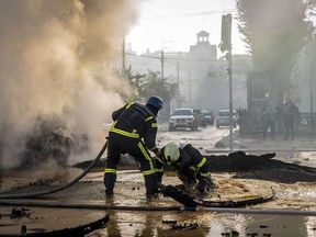 A firefighter helps his colleague to escape from a crater as they extinguish smoke from a burned car after a Russian attack in Kyiv, Ukraine, Monday, Oct. 10, 2022. Russia unleashed a lethal barrage of strikes against multiple Ukrainian cities Monday, smashing civilian targets including downtown Kyiv where at least six people were killed amid burnt-out cars and shattered buildings. The onslaught brought back into focus the grim reality of war after months of easing tensions in the capital.