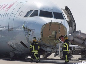 Airport firefighters work at the crash site of Air Canada AC624 that crashed early Sunday morning during a snowstorm, at Stanfield International Airport in Halifax on Monday, March 30, 2015.