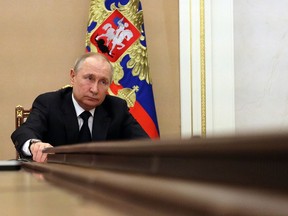 Russian President sits at a long table for a meeting.