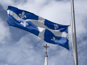The Quebec flag flies on a flagpole near a church in Gatineau, Que., Tuesday, Aug. 16, 2022.