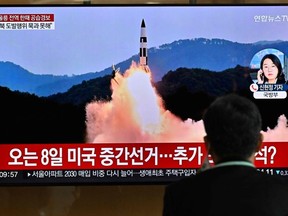 A man watches a TV screen showing a news broadcast with archival footage of a North Korean missile test, at a train station in Seoul on November 2, 2022.