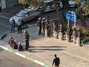 Iranian women sit without veils across from security forces in a square in Tehran on Oct. 27.