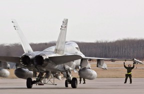 Military personnel guide a CF-18 Hornet into position at the CFB Cold Lake, in Cold Lake, Alta.