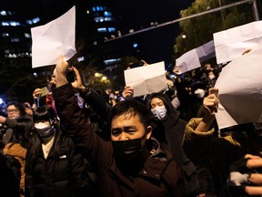 Protesters in Beijing hold sheets of white paper.