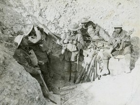Canadians take a break in a captured German trench during the Battle of Hill 70 in August 1917. The soldiers on the left are scanning the sky for aircraft, while the soldier in the centre appears to be re-packing his gas respirator into the carrying pouch on his chest. Dust cakes their clothes, helmets, and weapons.