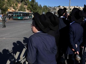 Yahudi gençler, 23 Kasım 2022'de Kudüs'te bir otobüs durağında meydana gelen patlamanın ardından olay yerinde çalışan İsrail güvenlik güçlerini izliyor.
