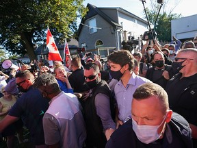 Prime Minister Justin Trudeau is escorted by his RCMP security detail as protesters shout and throw rocks during an election campaign stop at a local micro brewery in London, Ont., on Sept. 6, 2021.