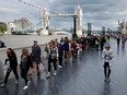 People walk in line along The Queens Walk near Tower Bridge as they march toward the public viewing of Queen Elizabeth II lying in state at Westminster Hall on September 15, 2022 in London, England.