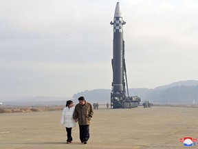 This picture released from North Korea's official Korean Central News Agency (KCNA) on November 19, 2022 shows Kim Jong Un (R) walking with his daughter as he inspects a new intercontinental ballistic missile (ICBM).