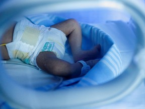 A newborn baby lies in an incubator.