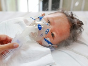 A sick baby in hospital wearing an inhalation mask to fight RSV.