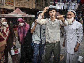 A Uyghur man tries on a hat as he buys new clothes at a market in old Kashgar, Xinjiang Province, China. According to official documents, the city of Kashgar put aside 20,000 yuan annually for "ethnic intermarriage awards."