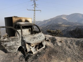 FILE - A charred truck is pictured after a fire near the village of Achlouf, in the Kabyle region, east of Algiers, Friday, Aug. 13, 2021. An Algerian court sentenced 49 people to death Thursday, Nov. 24, 2022 for the brutal mob killing of a painter wrongly suspected of starting devastating wildfires. In fact the man had come to help fight the fires. The 49 people will likely serve life in prison instead because Algeria has a moratorium on executions.