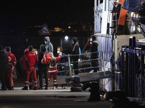 Migrants disembark from the Humanity 1 rescue ship run by the German organization SOS Humanitarian, in the port of Catania, Sicily, southern Italy, early Sunday, Nov. 6, 2022. Italy allowed the Humanity 1 rescue ship carrying over 100 migrants to enter the Sicilian port and begin disembarking minors, while refusing to respond to requests for safe harbor from three other ships carrying 900 more people in nearby waters.