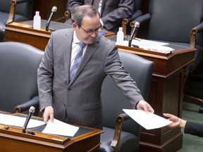 Ontario Attorney General Doug Downey hands over paperwork to a page in the Queens Park Legislature, in Toronto, on Thursday June 10, 2021. Downey says allowing prospective jurors to complete their questionnaire online is "the next evolution" in introducing a more modern way jury selection and management.