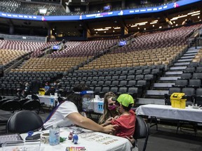 Seven-year-Austin Soissa prepares to receive his COVID-19 vaccine shot from Dr. Chetana Kulkarni from Sick Kids Hospital at a children's vaccine clinic held at the Scotiabank Arena, in Toronto, on Sunday, December 12, 2021.THE CANADIAN PRESS/Chris Young